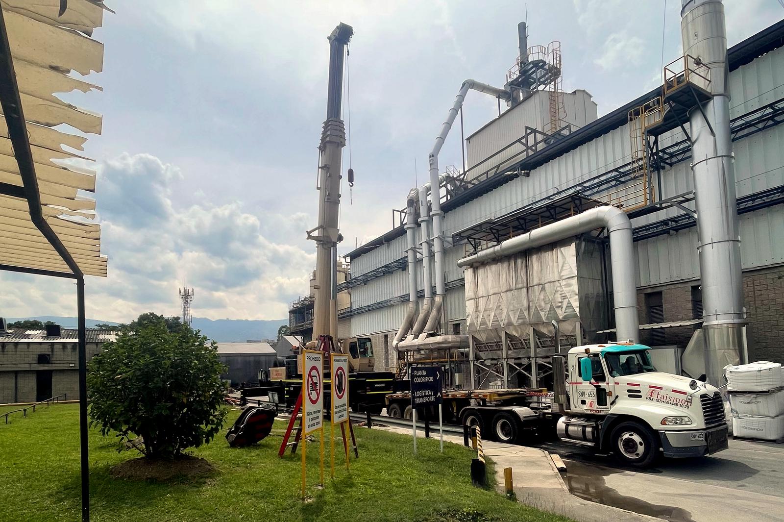 Planta industrial con chimeneas, ductos y grúa móvil; acompañamiento SST en instalaciones de proceso.