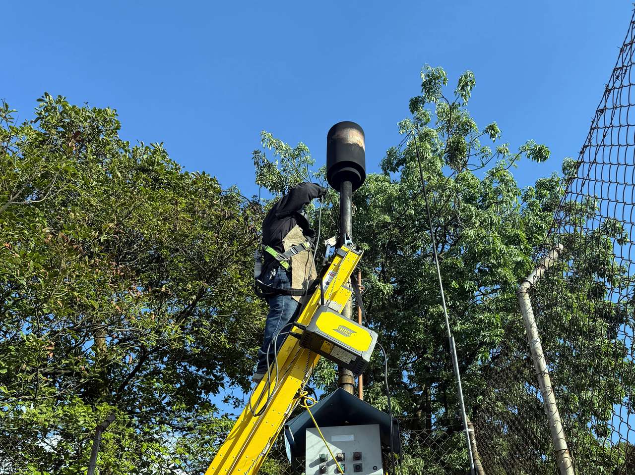 Trípode de rescate con malacate y trabajador con arnés; equipo SST para espacios confinados y rescate.